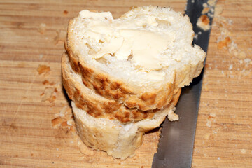 Sliced and buttered French stick baguette bread ready for dinner food prep with knife