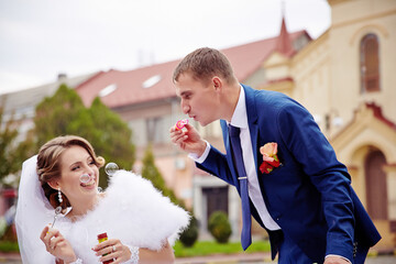 A bride and groom are blowing bubbles and the bride is wearing a white dress