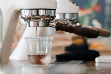 Barista preparing espresso with a modern coffee machine at a stylish café. Close-up of hand using...