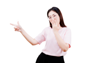 Asian young beautiful woman wearing glasses and a light pink shirt is making a finger gun gesture with one hand and covering her mouth with the other.