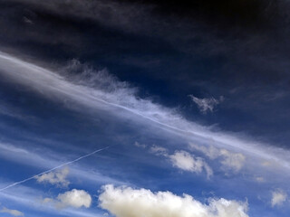 Close up of atmospheric blue black sky with whispy white clouds