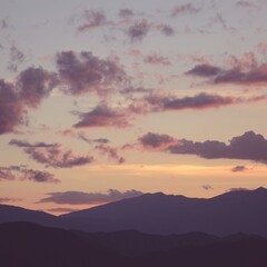 Soft purple - pink clouds drift across a twilight sky, with mountain silhouettes in deep hues...