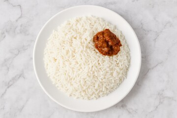 Top-down view of plain boiled rice served with pickle on a plate against a marble surface