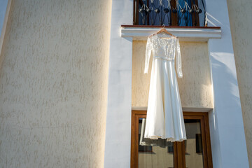 Dress on balcony by day. White wedding dress displayed on a balcony, illuminated by sunlight,...