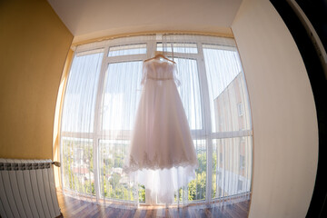 Wedding dress displayed by a window. A wedding dress elegantly hangs by a window, illuminated by...