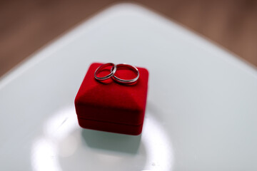 Rings on a red velvet box. Two silver wedding rings are placed elegantly on a red velvet ring box,...
