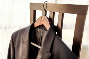 Suit hanging on a chair in a bright room. A neatly hung suit on a wooden chair in a well-lit room,...