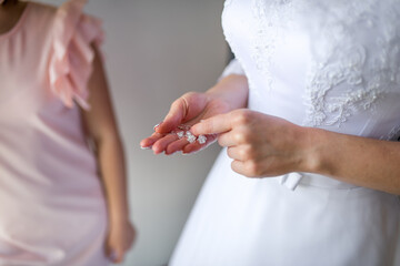 Bride prepares for wedding ceremony. A bride holds her hair accessory, getting ready for the wedding while a friend assists her in the background.