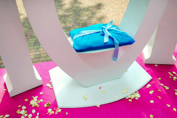 Colorful gifts at event. A blue gift sits on a stand, surrounded by colorful petals, ready for an...
