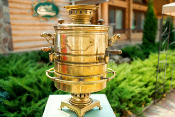 Brass samovar in the garden. A brass samovar decorates a rustic venue, surrounded by lush greenery...