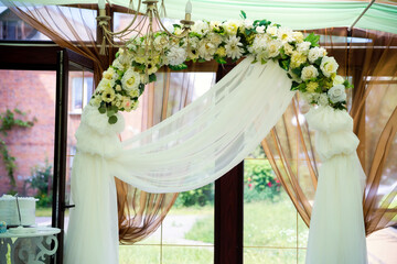 Elegant floral arch for wedding event. A stunning floral arch of white and yellow flowers, draped...