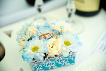 Elegant wedding rings and flowers. Two wedding rings rest on a decorative floral arrangement, showcasing a romantic moment at a wedding celebration.