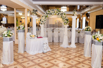 Elegant wedding setup in a banquet hall. A beautifully decorated banquet hall with floral...