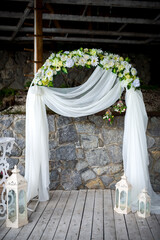 Floral wedding altar decor. A stunning altar with white drapes and flowers stands against a stone backdrop, perfect for a wedding.