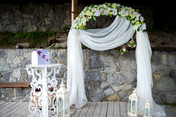 Decorated wedding arch. A decorative wedding arch is adorned with flowers and drapes, set against a...