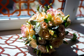 Flower bouquet by window. A vibrant bouquet of roses and other flowers rests elegantly on a table near a sunlit window.