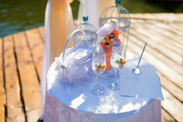 Outdoor celebration table decor. A beautifully arranged table features glasses, flowers, and decorations ready for a joyful outdoor event by the water.