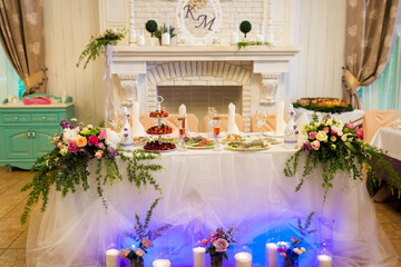 Elegant wedding reception table setup. Floral arrangements and decorative dishes adorn a beautifully arranged wedding reception table by a cozy fireplace.