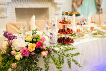 Chic table for festive vibes. Beautifully arranged table features fresh flowers, fruits, and elegant glassware for a special event celebration.