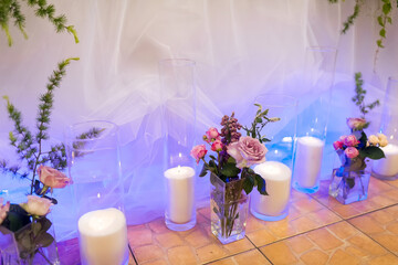 Floral and candle display. Beautiful flowers and candles are arranged in glass vases, creating a romantic atmosphere for an event.