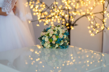 Lovely bouquet in soft light. A bride's bouquet of white and pastel roses shines with warm fairy lights, creating a romantic vibe.