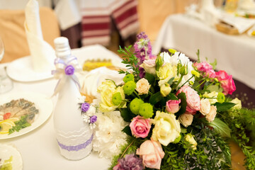 Floral centerpiece on table. A colorful floral centerpiece with roses and greenery adorns a...