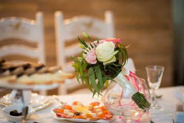 Lovely flowers on table. Elegant flowers are displayed in a glass vase on a beautifully set dining table featuring various appetizers.