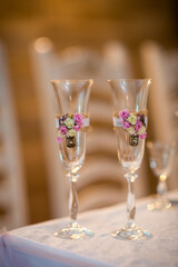Floral celebration glasses. Two beautifully decorated glasses with floral accents sit on a table, ready for a festive occasion indoors.
