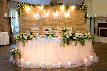 Chic wedding hall decor. Beautifully arranged wedding reception features floral decorations and a romantic atmosphere for a just married couple.