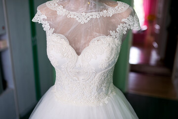 Elegant lace wedding dress in soft light. A stunning white wedding dress hangs elegantly,...