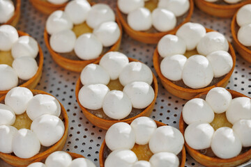 Closeup of freshly baked tartlets with white meringue and lemon filling in bakery factory