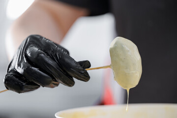 Gloved hand dipping pastry chocolate potato at bakery factory