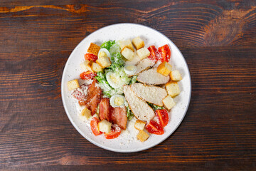 Delicious salad featuring grilled chicken, fresh vegetables, and croutons served on a wooden table