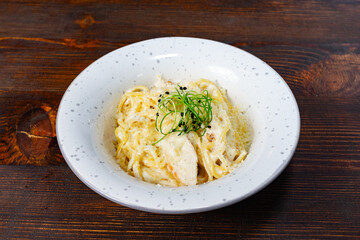 Delicious creamy pasta dish served in a stylish white bowl on a rustic wooden table