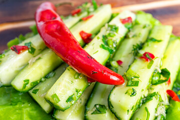 Fresh cucumber salad with red chili and herbs garnished on a wooden platter