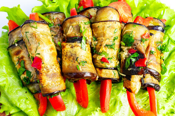 Grilled vegetable skewers featuring eggplant and bell peppers arranged on fresh lettuce