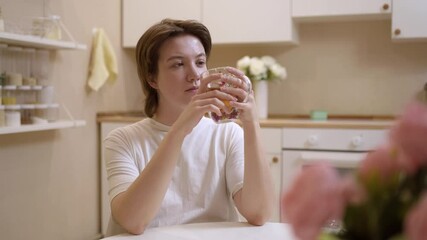 A young woman enjoys a simple meal and drinks tea in her cozy kitchen. Authentic, unposed moment capturing real emotions and the warmth of everyday life. Perfect for lifestyle and food content