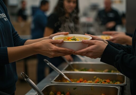 A bowl of hot, steaming soup being passed from one set of hands to another.