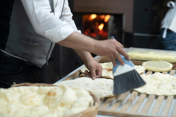 Male hands brushing freshly baked famous flat bread called lavaş in front of a wood burning fire in a traditional bakery in Turkey
