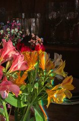 Colorful alstroemeria flowers with rainbow reflection in a dark cupboard