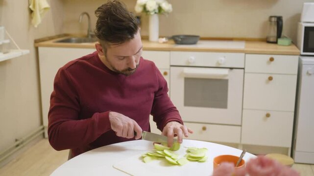 A 30-year-old man enjoys a casual meal and drink in his kitchen, captured in a natural, unposed moment. Authentic and relatable everyday scene perfect for lifestyle and food content
