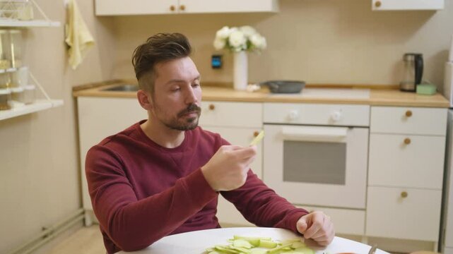 A 30-year-old man enjoys a casual meal and drink in his kitchen, captured in a natural, unposed moment. Authentic and relatable everyday scene perfect for lifestyle and food content