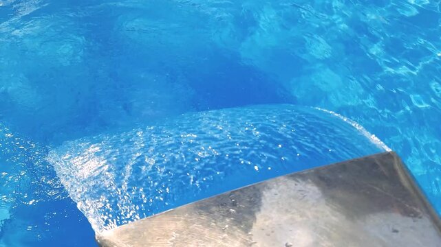 Video footage of blue clear water falling into a blue pool.