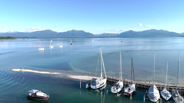 Wundervolle Sommerlandschaft am Chiemsee aus der Drohnenperspektive mit Seegelboten im Hafen
