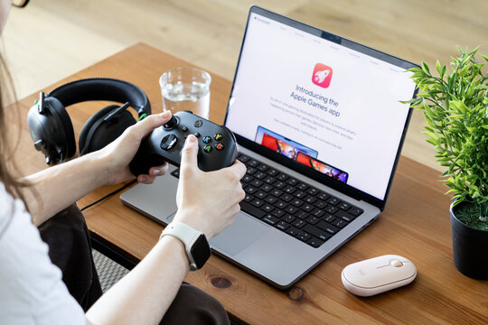 Poznan, Poland - June 15, 2025: Introducing the Apple Games app on an Apple MacBook Pro, with a person's hands holding an Xbox controller for gaming fun