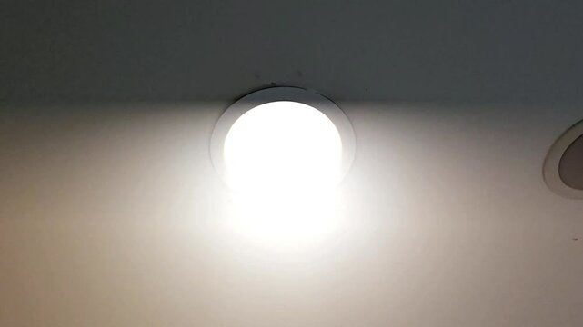 bright, circular recessed light fixture emitting an intense, almost blinding white glow from a light-colored ceiling.