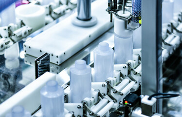 White plastic bottles in a conveyor belt on a high quality automatic vertical filling machine. in the factory production line