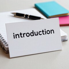Obraz premium Simple Desk Setup with Notepad, Pen, and Card Displaying the Word Introduction for Learning Concept