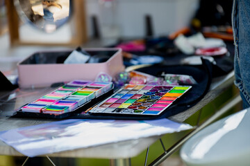 colorful face painting palette on artist table during outdoor event with makeup accessories bright...