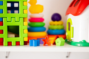 Bright educational toys arranged on a shelf: pyramids, wooden shapes, rings. Perfect for blogs,...
